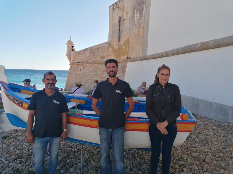 Sesimbra Team fort.jpg Three persons in front of a local fishing boat, an aiola, in Sesimbra.